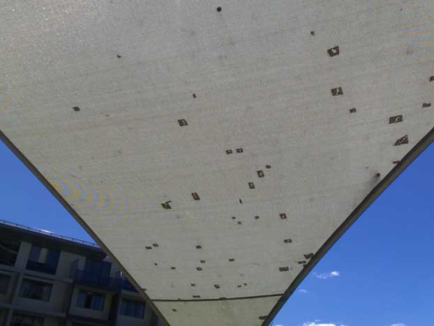 Every sail is damaged. The blackened sections are where a repairer had sewn patches to plug the holes.