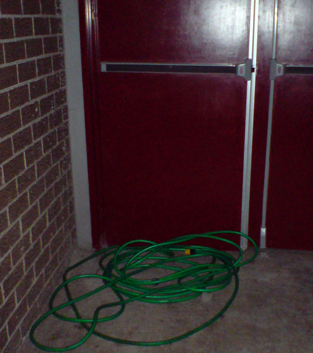 Beyond the brick was this garden hose. It was not visible in the dark. Here, it is visible due to the camera flash. This is completely against all fire-exit regulations. The hall was crowded with people, including from infants to frail senior citizens. 